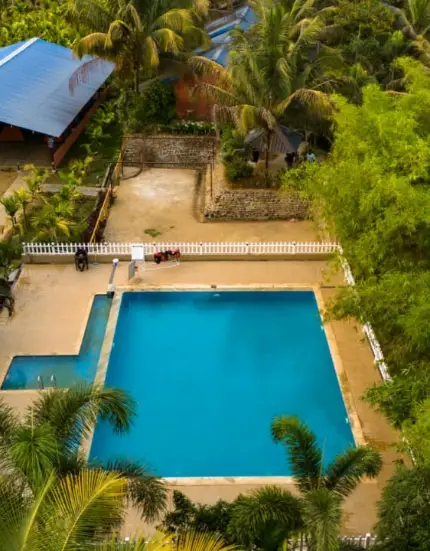 Refreshing swimming pool at a Dandeli resort surrounded by lush greenery, perfect for relaxation and adventure seekers.